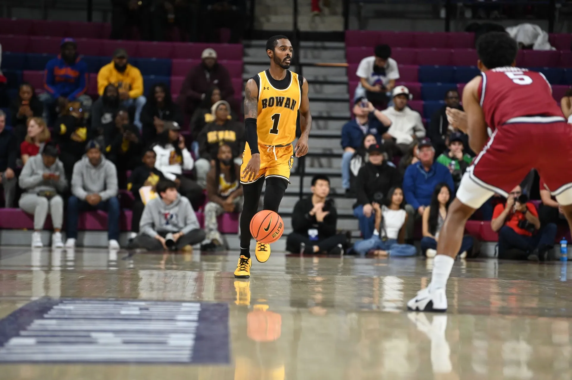 Fareed Burton Jr. in a yellow Rowan College number one jersey dribbling in an arena